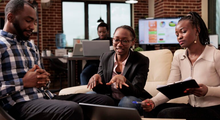 Team of employees working on business report, using data and information on documets to plan presentation. Doing teamwork and brainstomring ideas to create company research project.